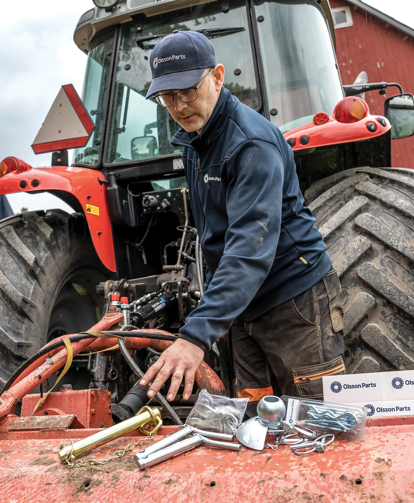 En person sträcker sig efter reservdelar placerade bakom en Massey Ferguson traktor.