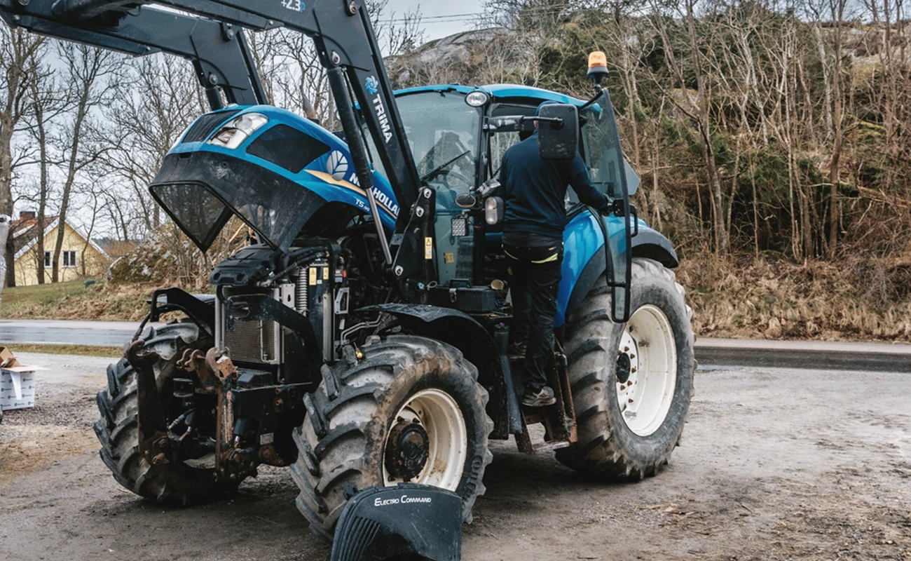 En person mekker p&aring; en New Holland-traktor.