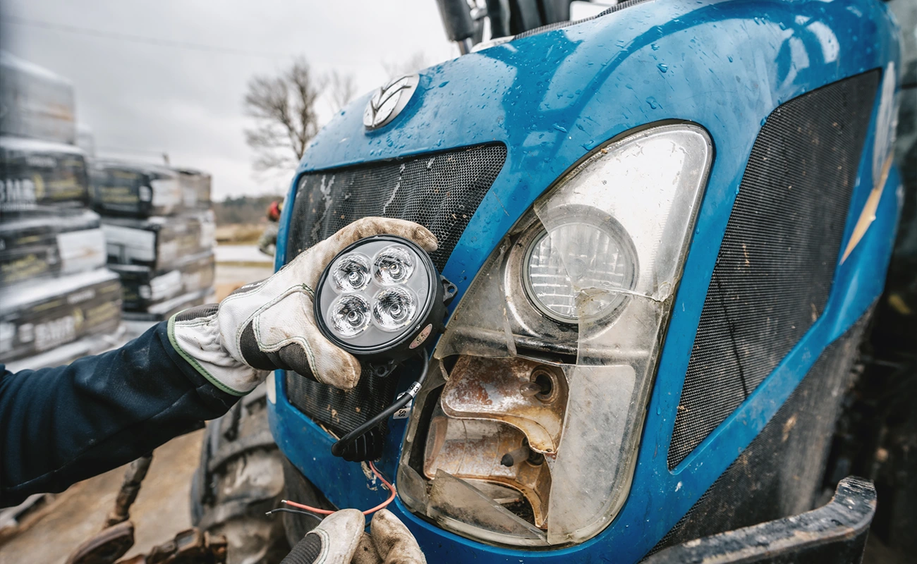 En person monterar en lampa på en New Holland-traktor.