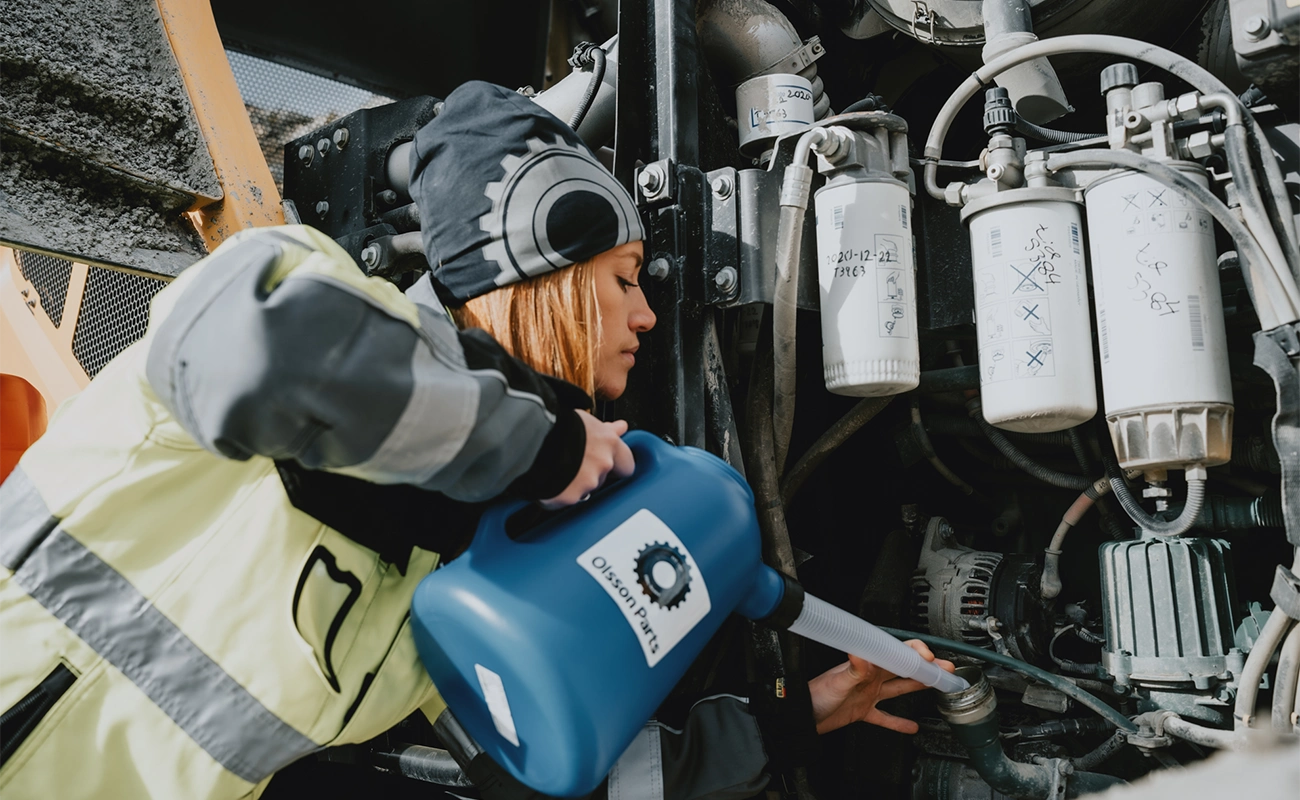 En person fyller p&aring; olja p&aring; en hjullastare.