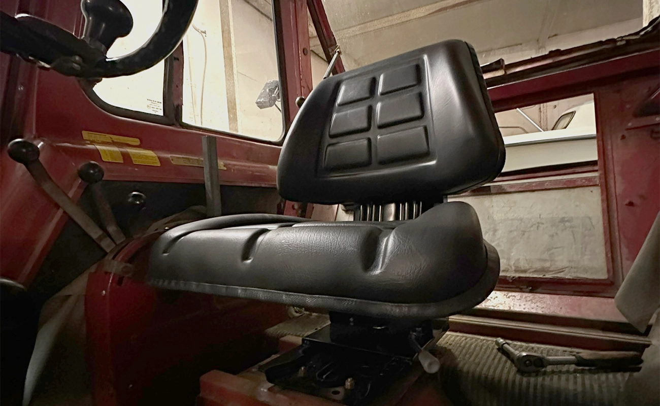 Et svart sete montert i en traktorkabin.