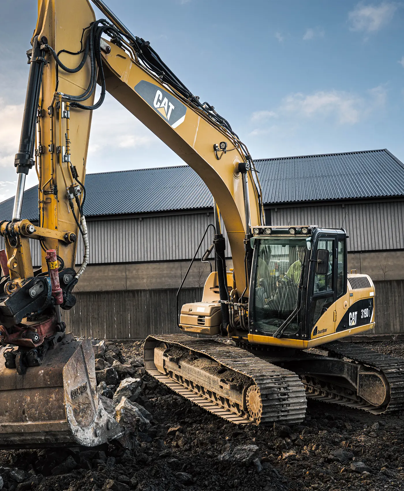 En Caterpillar gravemaskine arbejder p&aring; en grusplads.