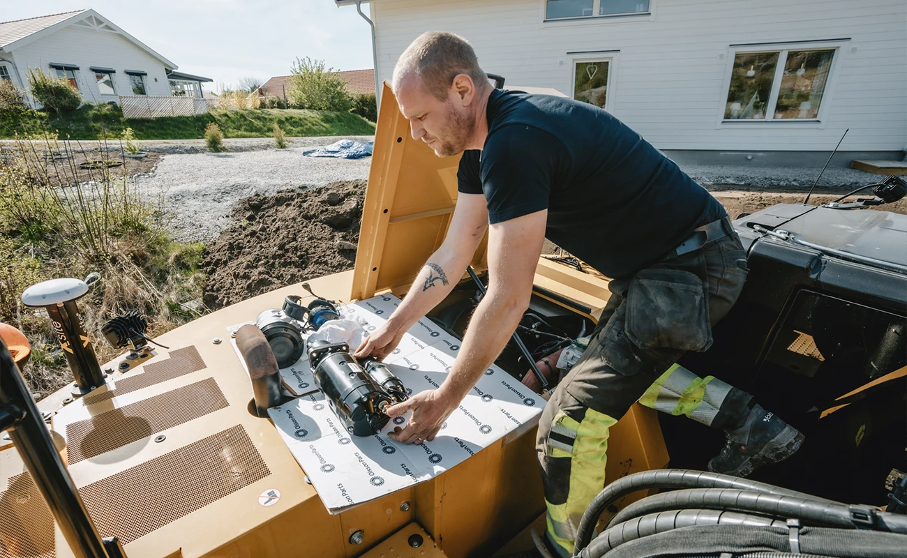 En person monterer en startmotor p&aring; en Caterpillar gravemaskine.