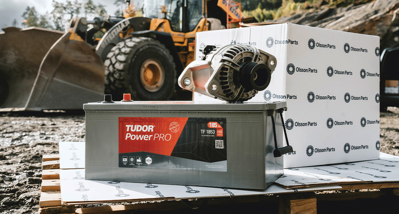 Ett Tudor Power PRO fordonsbatteri st&aring;r placerat p&aring; en lastpall framf&ouml;r en Volvo hjullastare.