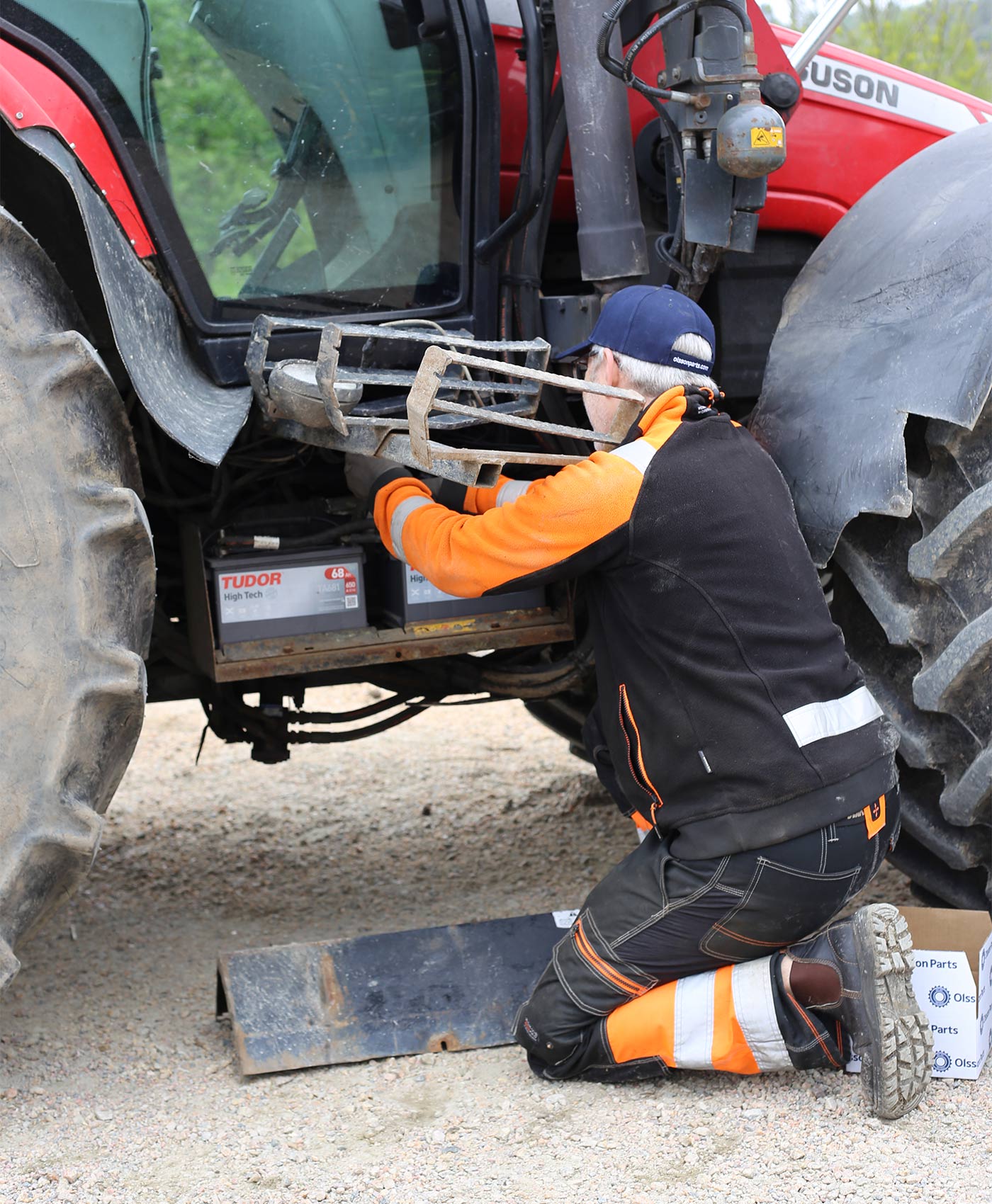 En mekaniker monterar ett Tudor High Tech batteri på en Massey Ferguson traktor.