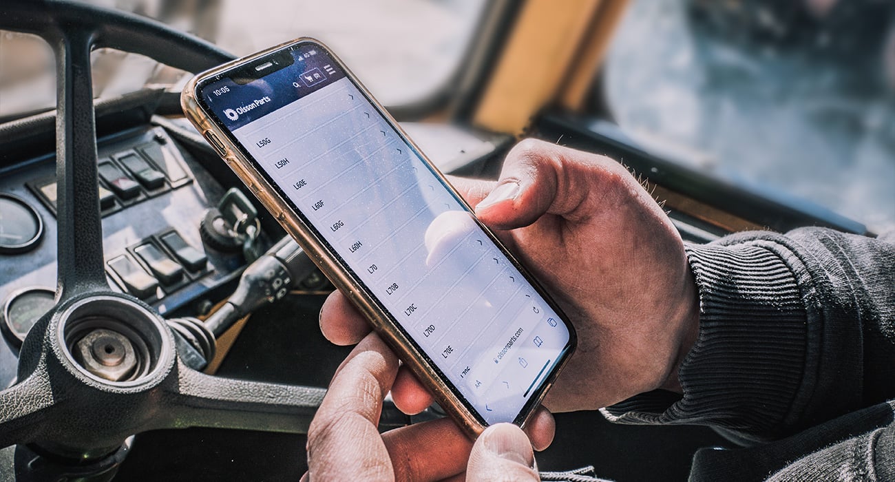 En person håller i en mobil med Olsson Parts hemsida på.
