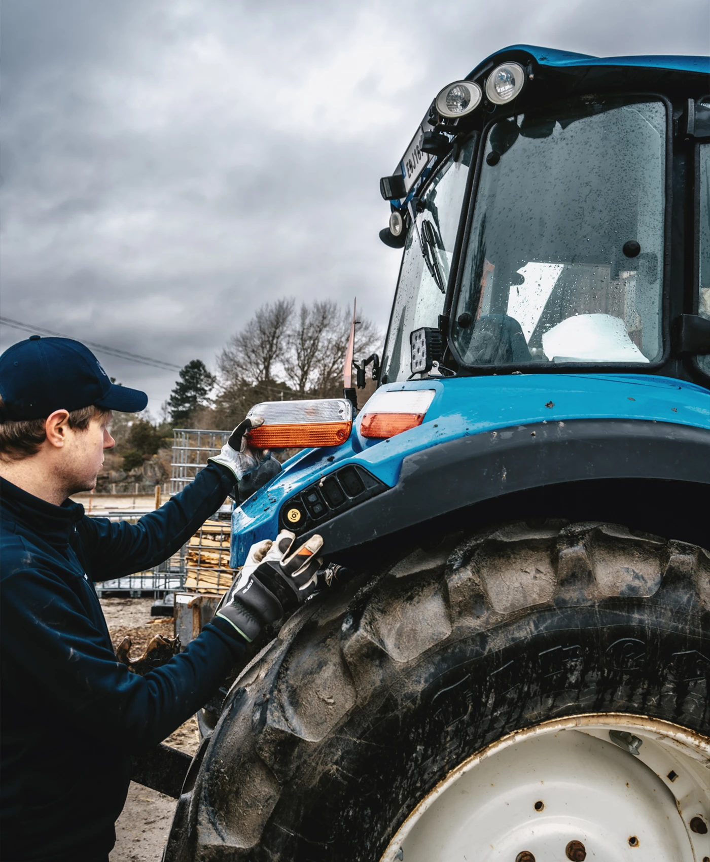 En person monterar bakljus p&aring; en New Holland-traktor.