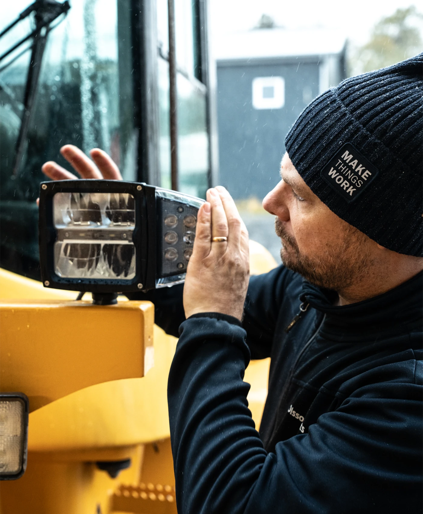 En person monterar en str&aring;lkastare p&aring; en Volvo hjullastare.