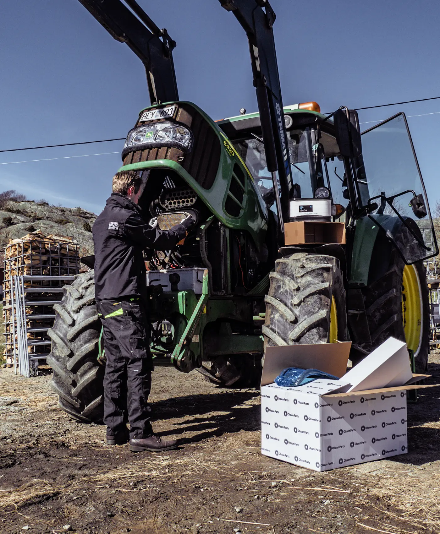 En person skifter filter p&aring; en John Deere-traktor.