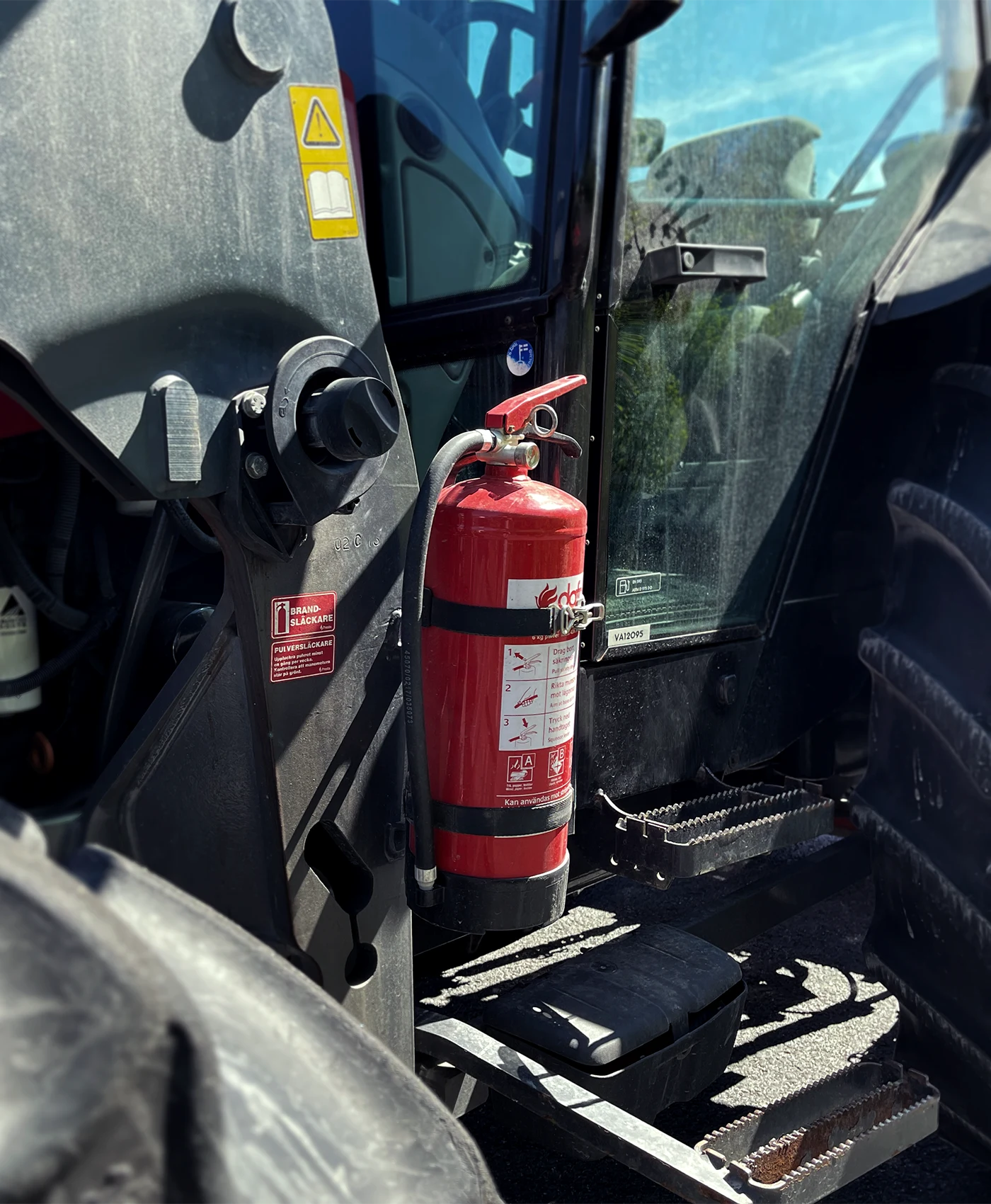 En brandslukker monteret ved f&oslash;rerd&oslash;ren p&aring; en traktor.
