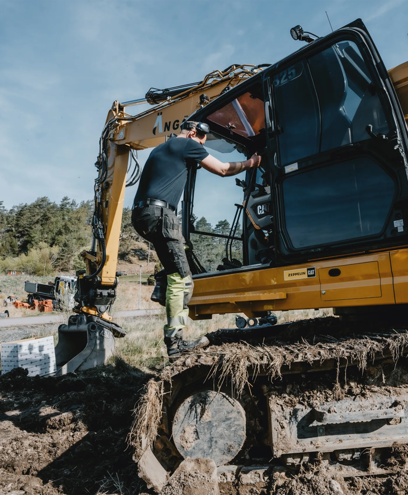 En person på vej ind i førerhuset på en Caterpillar gravemaskine.