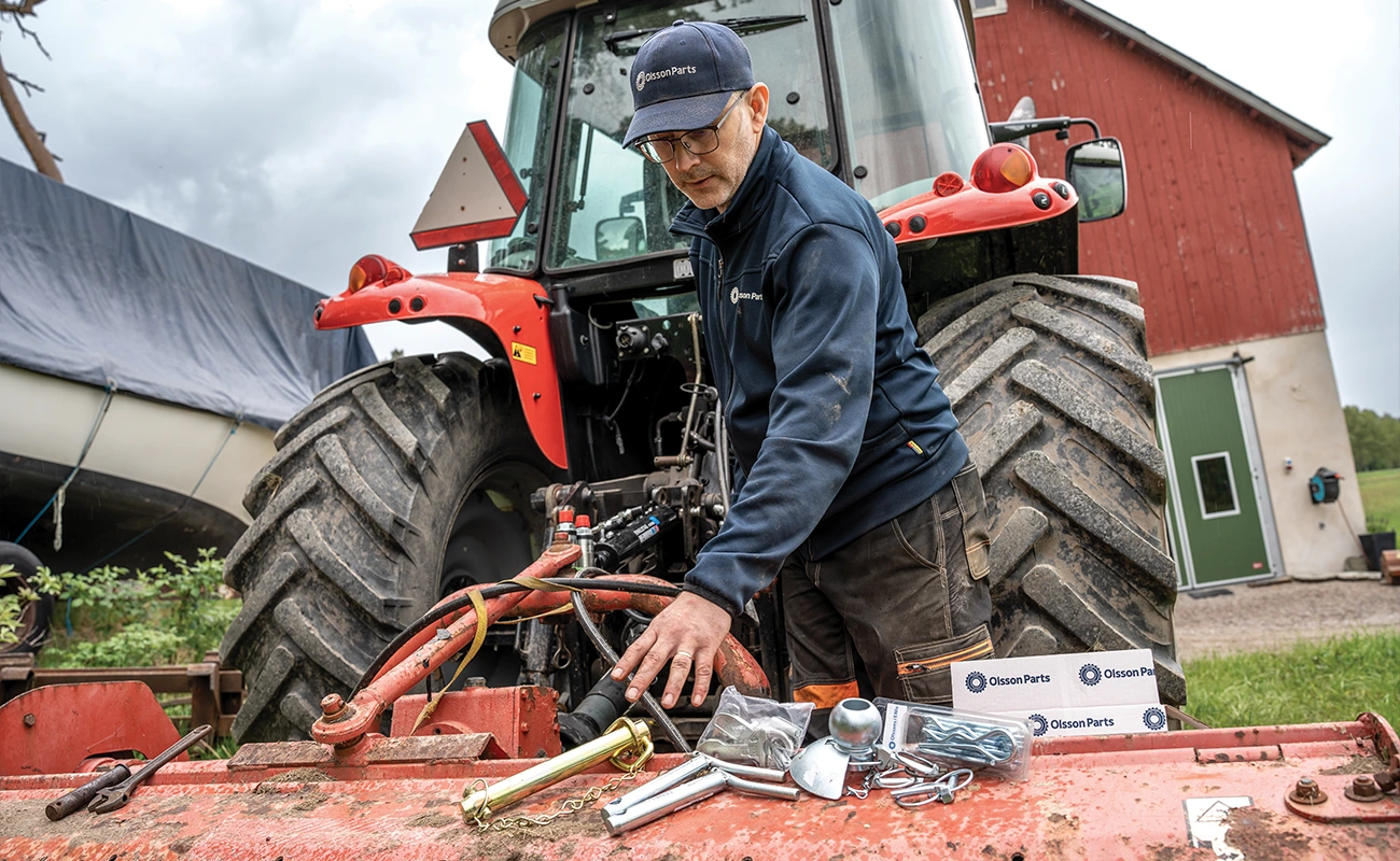 Eine Person greift hinter einem Massey Ferguson Traktor nach Ersatzteilen.