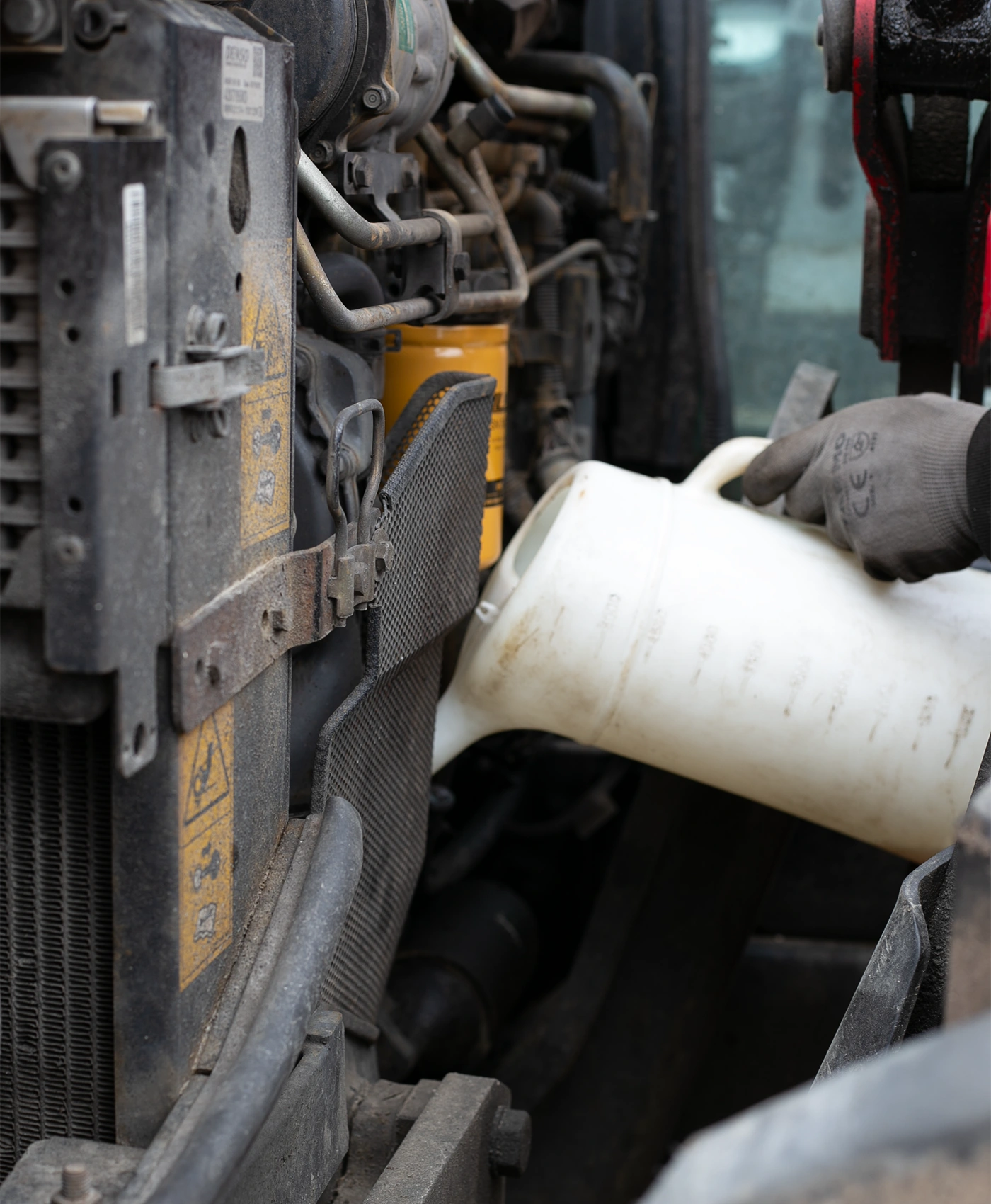 En person fyller olje p&aring; en Massey Ferguson traktor med en oljekanne.