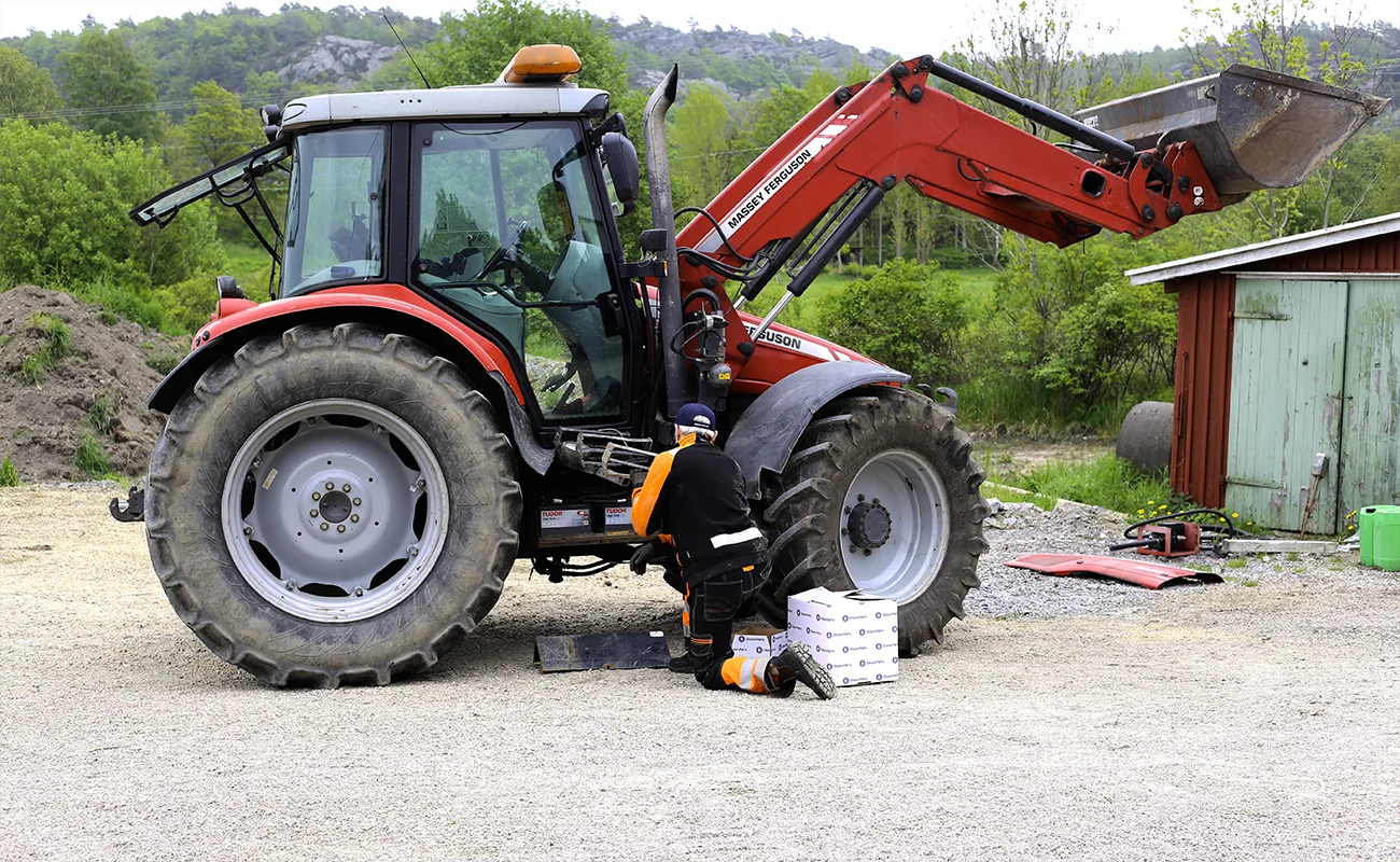 En person st&aring;r foran en Massey Ferguson traktor med esker fra Olsson Parts ved siden av seg.