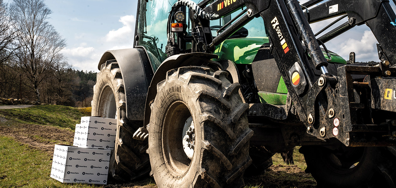 En grön Deutz traktor med Olsson Parts-lådor bredvid.