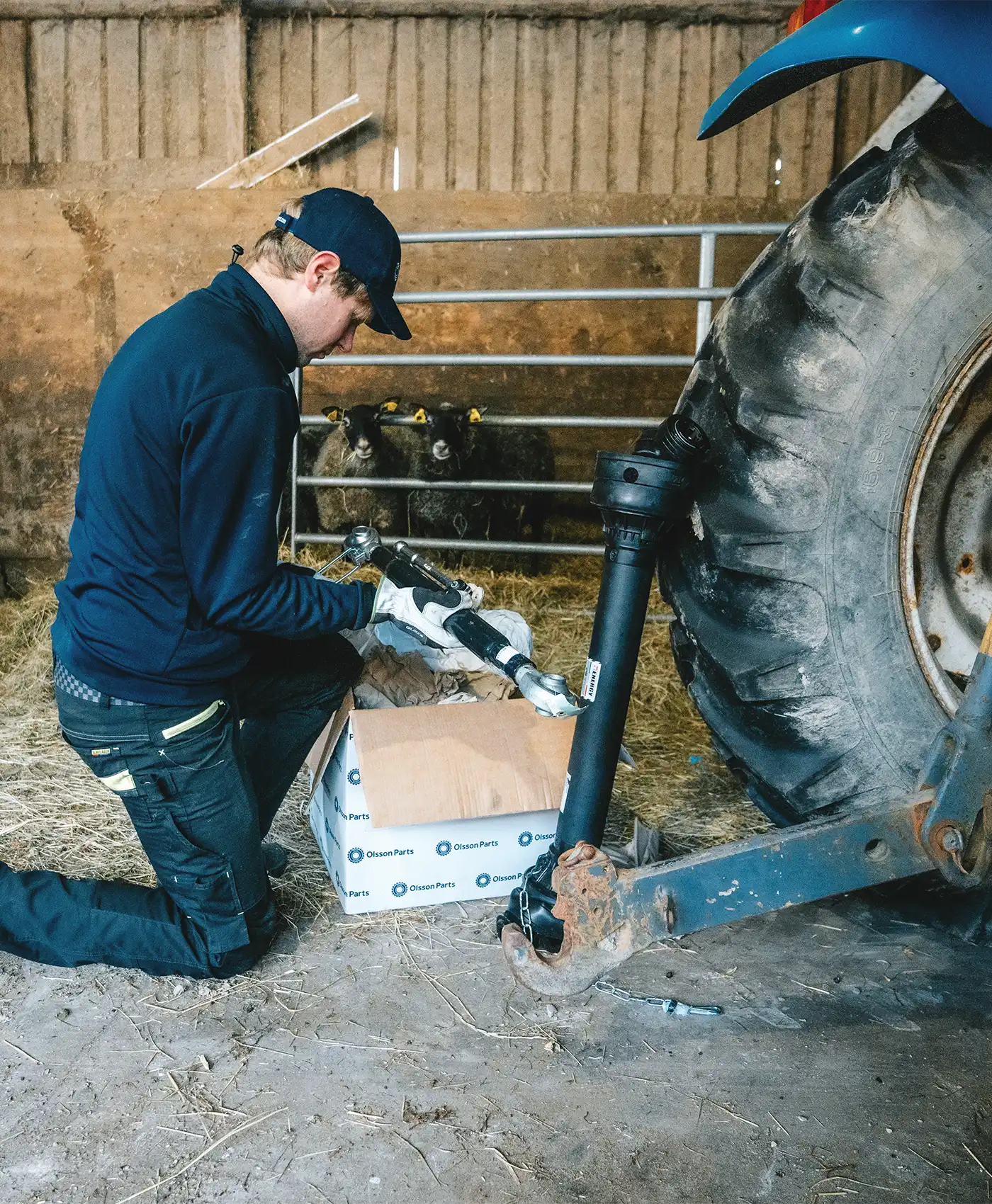 En person håller i ett toppstag bakom en New Holland-traktor.