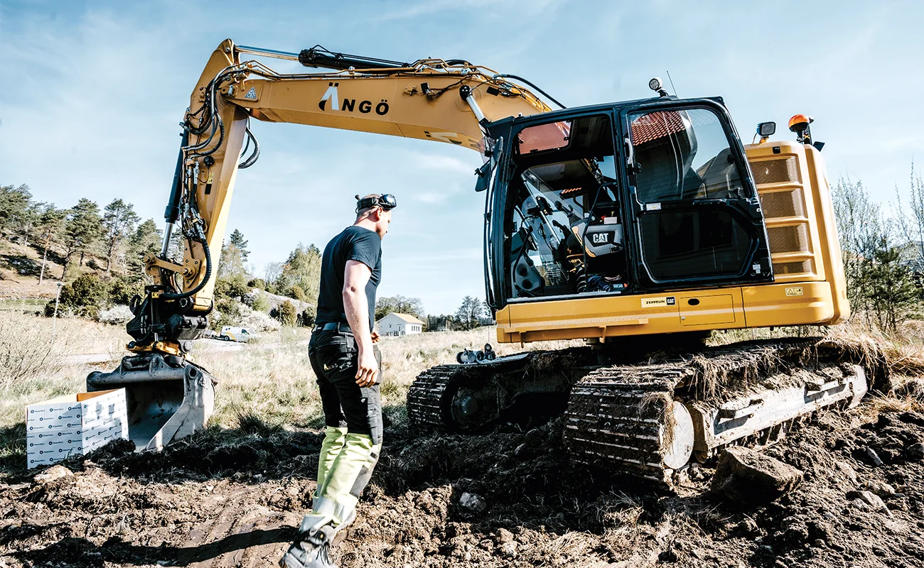 En person &auml;r p&aring; v&auml;g mot hytten till en Caterpillar gr&auml;vmaskin.