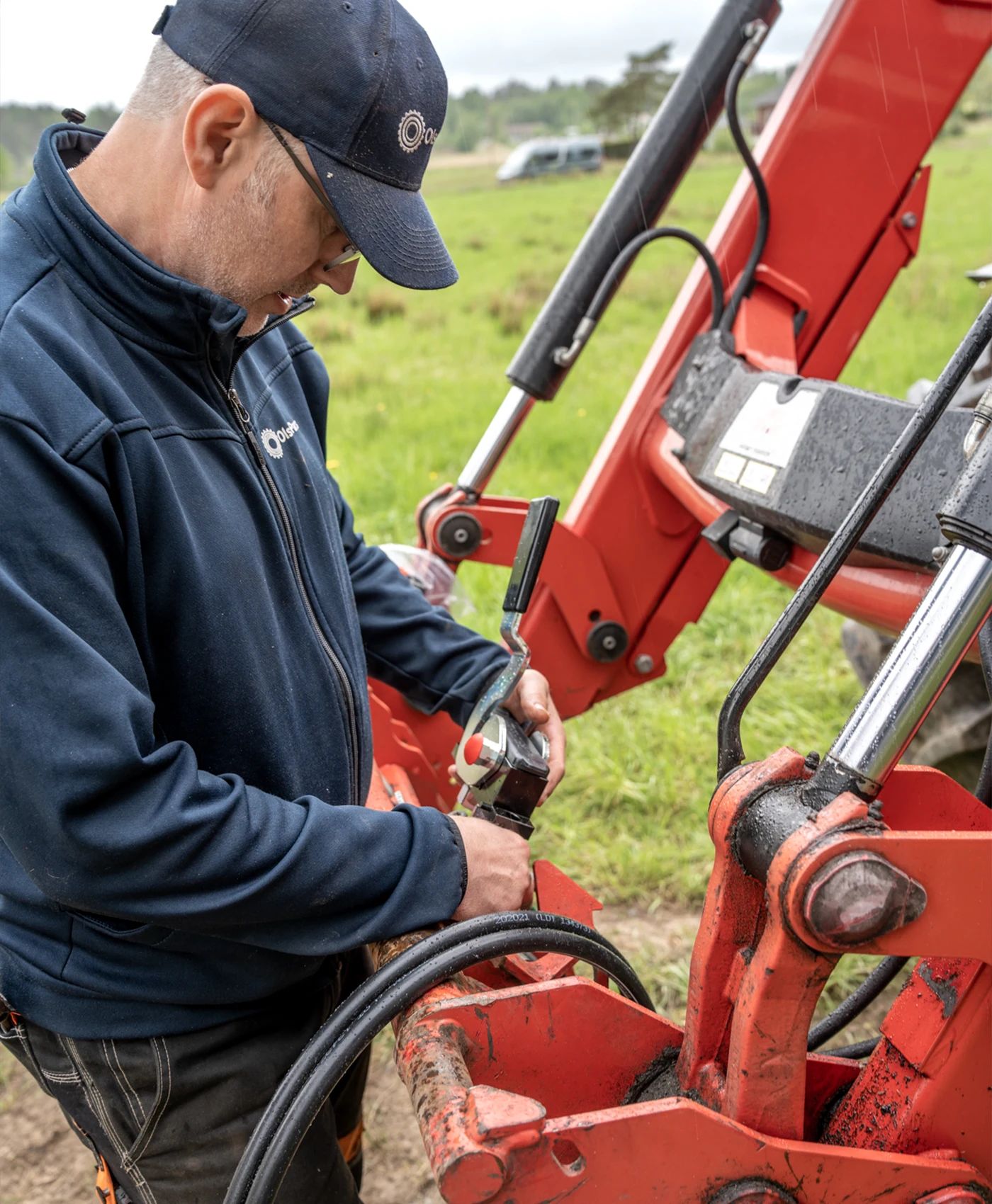 Person monterar en hydraulventil på en frontlastare på en traktor.