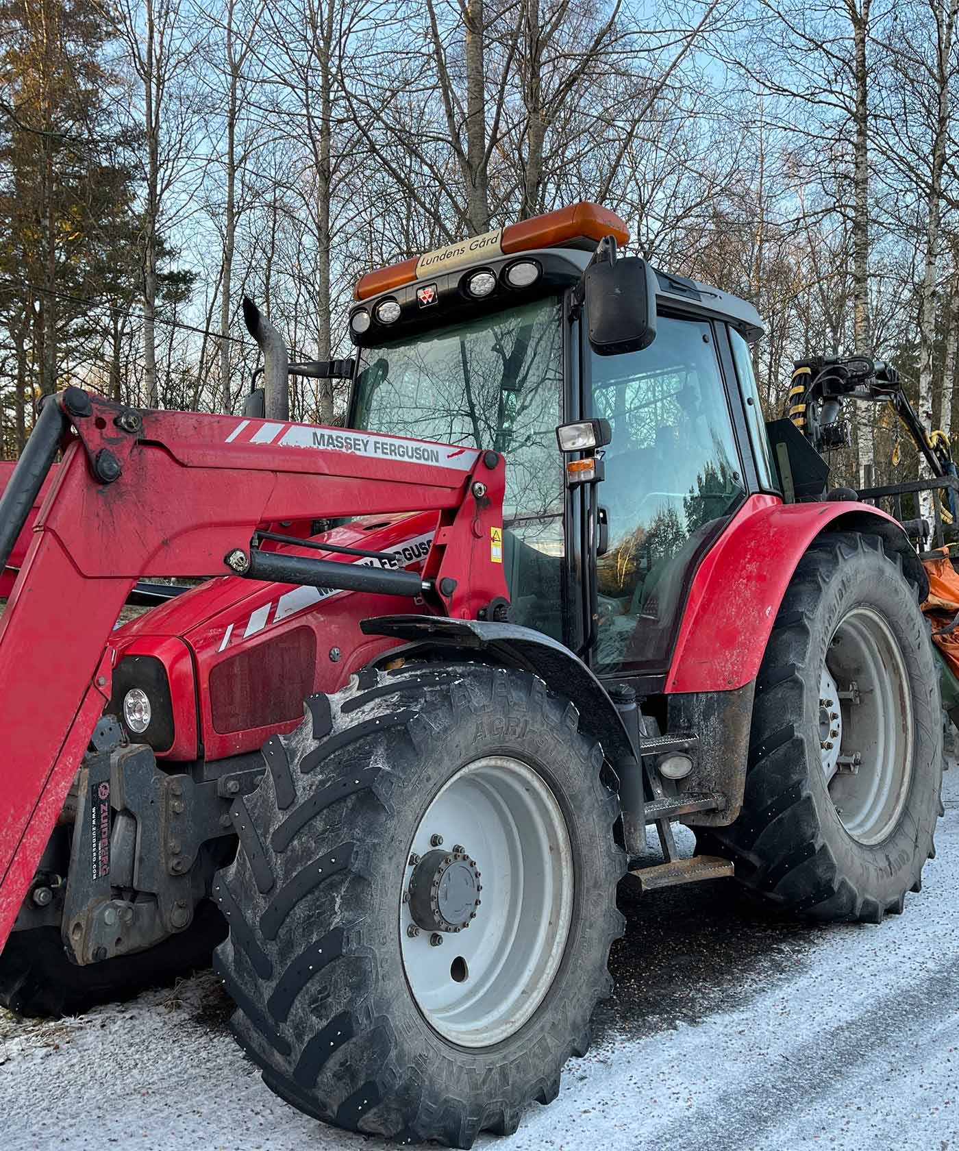 En Massey Ferguson står parkerad på en snötäckt väg.