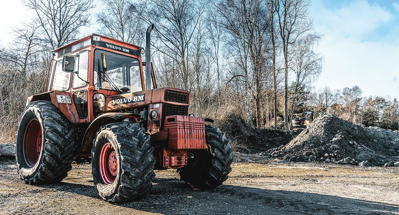 En Volvo BM står parkerad framför träd.