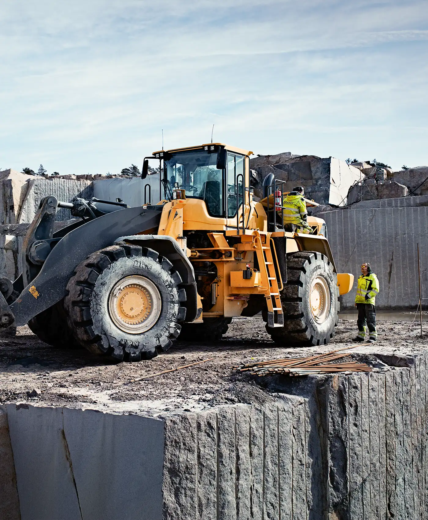 To personer arbejder på en Volvo gummiged på en arbejdsplads.