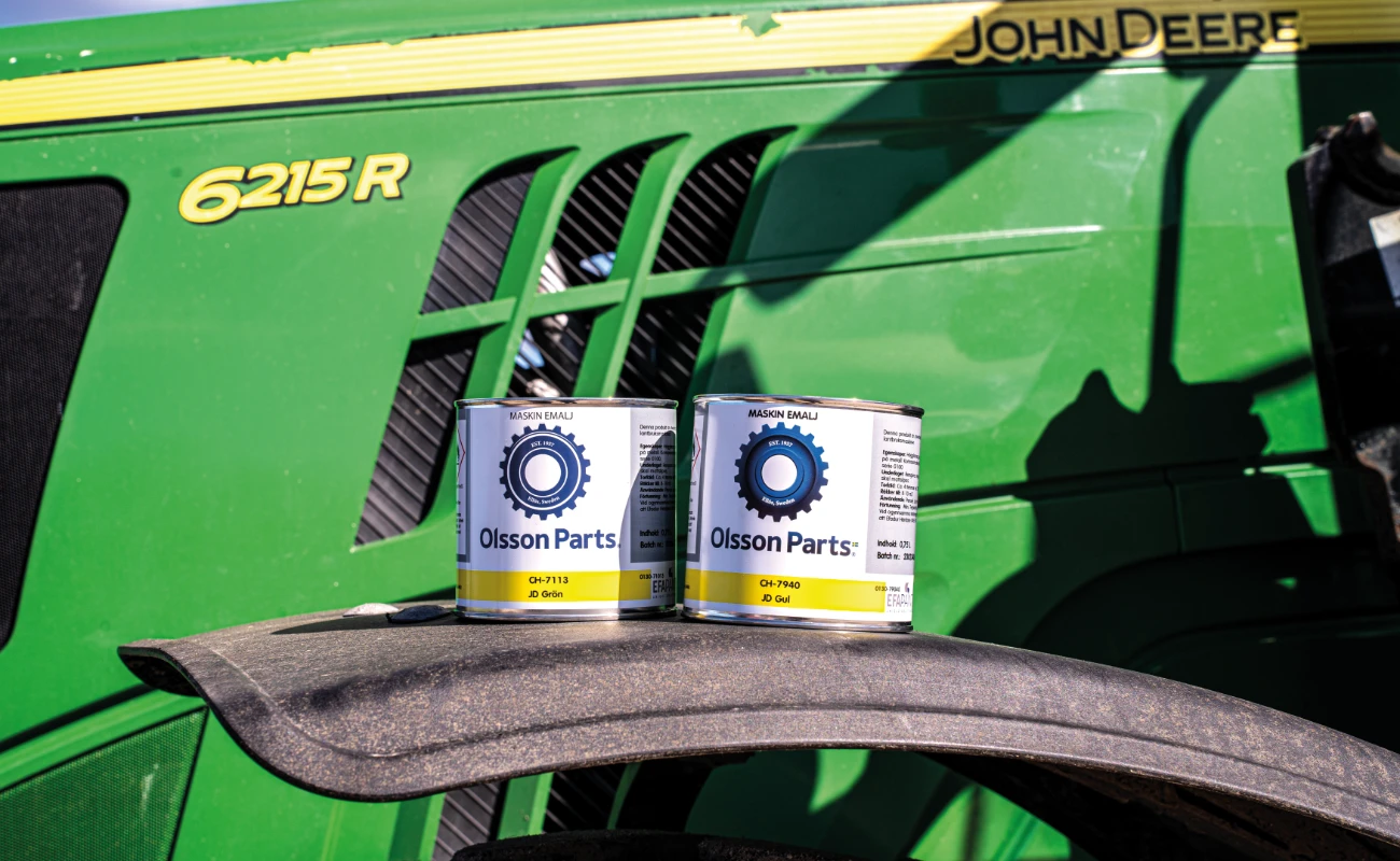 To malingsbokser fra Olsson Parts står plassert på forskjermen på en John Deere-traktor.