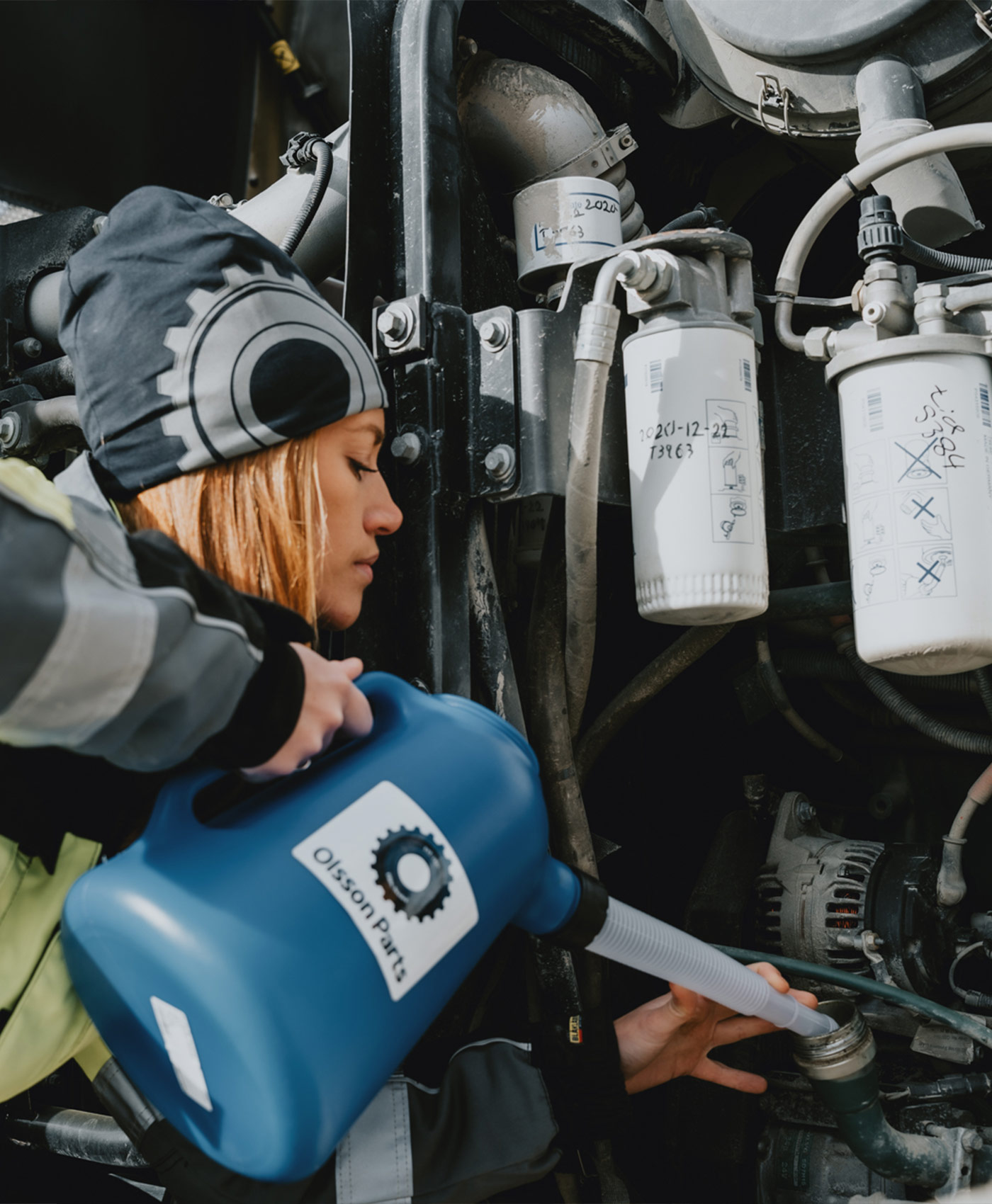 A person is pouring oil into the engine of a wheel loader.