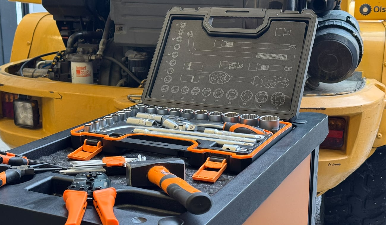 Olika verktyg placerade p&aring; en verktygsvagn. I bakgrunden st&aring;r en Volvo hjullastare parkerad.