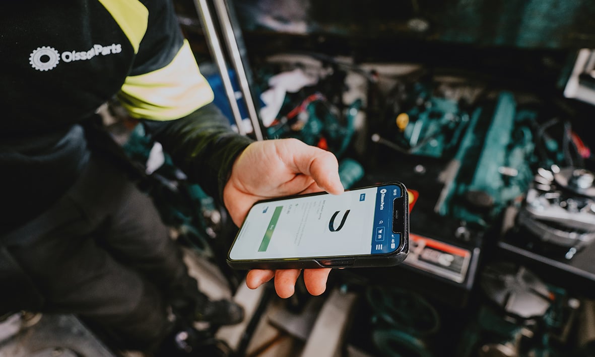 Zeigt die Olsson Parts Website auf einem Smartphone im Hochformat in einem Motorraum.