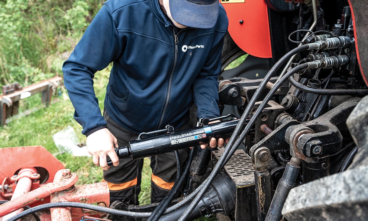 A person showing three-point hitch parts on a tractor.